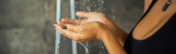シャワー、バナーで水の下に手を保持アフリカ系アメリカ人女性の作物ビュー  - 写真・画像