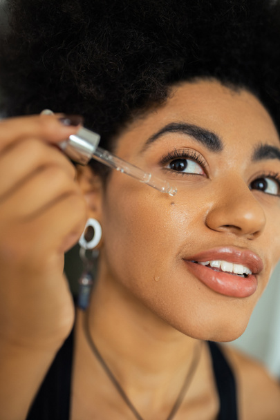 若いアフリカ系アメリカ人女性が自宅で頬に血清を適用  - 写真・画像