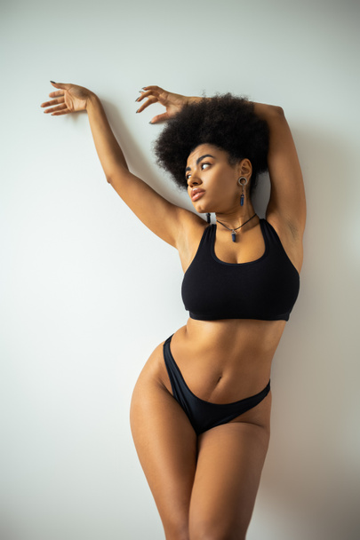 Sexy african american woman in crop top and panties posing near wall  - Photo, Image