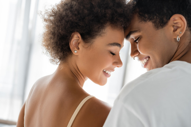 curly african american woman and man with piercing smiling with closed eyes  - Фото, изображение