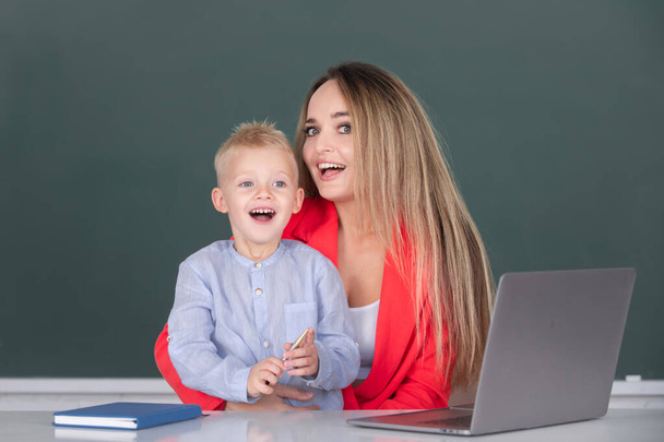 Little school child son using laptop with mother. Teacher tutor helping school child in class at school - Fotografie, Obrázek