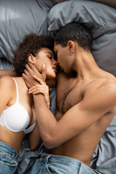 vista superior do homem americano africano sem camisa beijando mulher sexy no sutiã branco na cama - Foto, Imagem