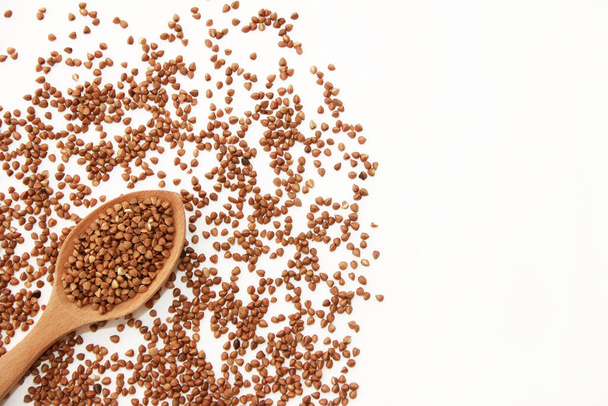small grains of natural brown buckwheat in a wooden spoon - Photo, image