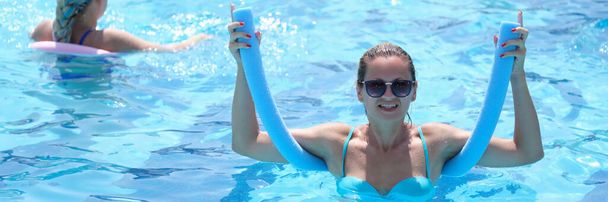 Felice donna fitness sorridente che si allena nella piscina di spaghetti. Sano concetto di allenamento aerobico. - Foto, immagini