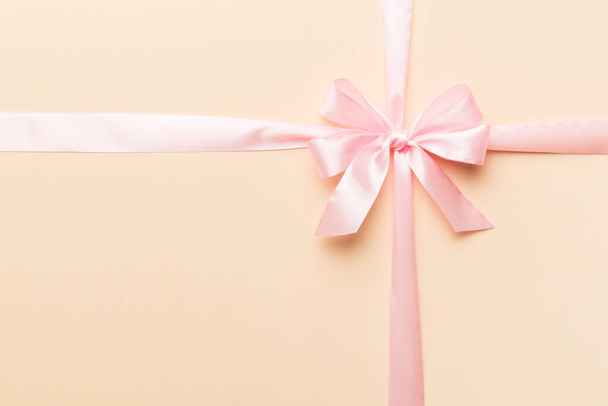 Top view of purple ribbon rolled and pink bow isolated on colored background. Flat lay with copy space. - 写真・画像