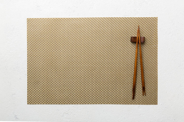 Dvě hůlky a bambusová rohožka na betonovém pozadí. Horní pohled, kopírovací prostor. - Fotografie, Obrázek