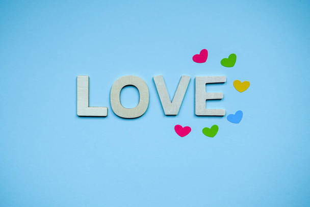 αγάπη ξύλινα γράμματα και σχήματα καρδιά στο μπλε φόντο για την ημέρα του Αγίου Βαλεντίνου  - Φωτογραφία, εικόνα