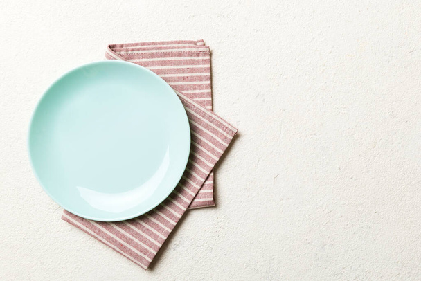 Κάτοψη σε έγχρωμο φόντο άδειο γύρο Μπλε πιάτο σε τραπεζομάντιλο για τα τρόφιμα. Κενό πιάτο σε χαρτοπετσέτα με χώρο για το σχεδιασμό σας. - Φωτογραφία, εικόνα