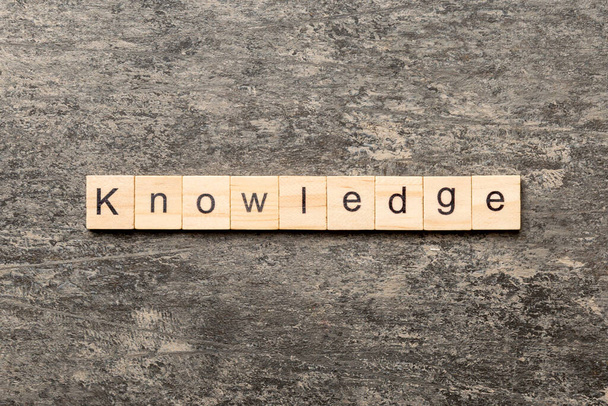 Palabra de conocimiento escrita en bloque de madera. Texto de conocimiento sobre mesa de cemento para su diseño, concepto. - Foto, imagen