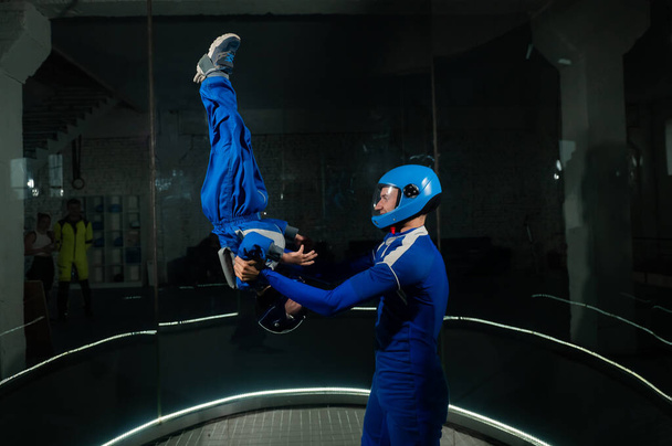 A man teaches a boy to fly in a wind tunnel. Lack of gravity - Zdjęcie, obraz
