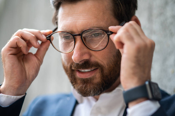 Eyeglasses. Headshot of a man putting on eyeglasses - Fotó, kép