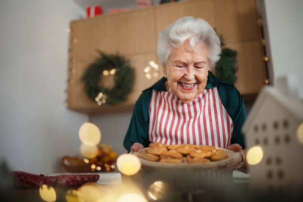 Happy senior woman baking a Christmas cakes at home. - Photo, image