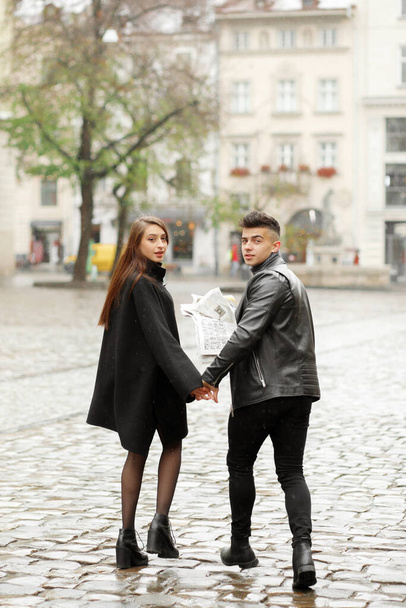 新聞を手に雨の街を歩く若いカップル - 写真・画像