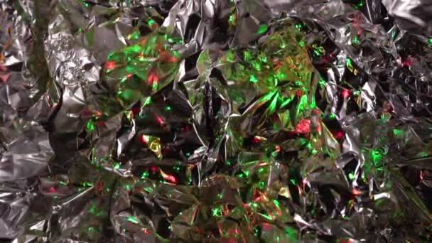 Zmačkaná fólie s barevnými světly, kovově lesklá textura - Záběry, video