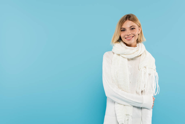 Pretty woman in warm scarf and sweater looking at camera isolated on blue  - Фото, зображення