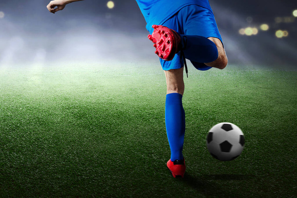 Rear view of a football player man in a blue jersey kicking the ball on the football field - Fotoğraf, Görsel
