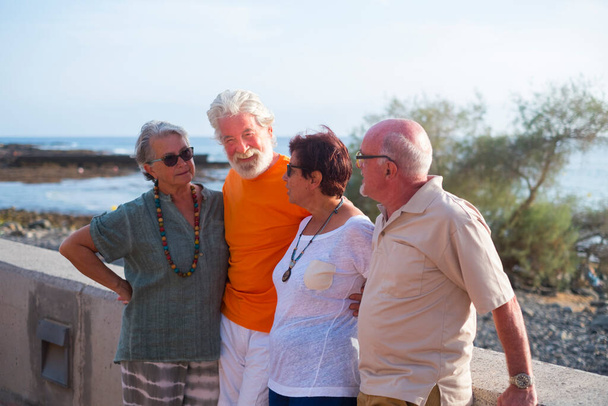 grupo de personas mayores y personas maduras en la playa tomando juntos y divirtiéndose con el mar o el océano al fondo - cuatro personas - Foto, imagen