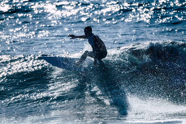 teenager surfing at the wave in tenerife beach of the americas - white and black wetsuits and beautiful and small wave  - Photo, Image
