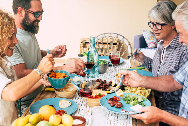 beautiful moment of family lifestyle at home eating food or drinking drinks at home on the table - man with sunglasses taking a vegetables - table full of food and salad outdoor    - Fotó, kép