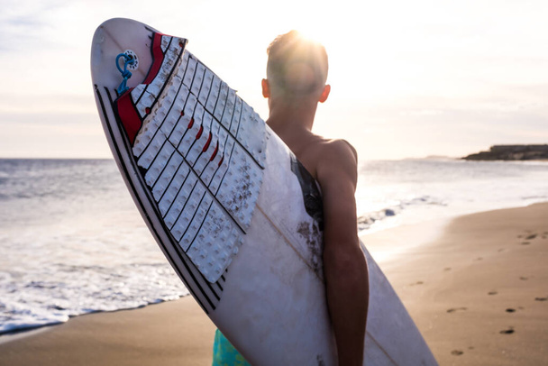 primer plano del hombre corriendo en la playa con su tabla de surf haciendo surf en verano con el atardecer  - Foto, imagen