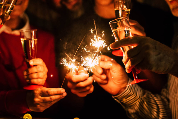 Близкие люди встречают Новый год с искрами и игристым вином - концепция ночной жизни - день рождения или вечеринка друзей, веселящихся вместе  - Фото, изображение