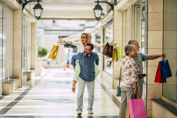 група з чотирьох чоловік і сім'ї йдуть по магазинах разом тримаючи багато сумки після покупки чорна п'ятниця або кіберпонеділок і час продажу
  - Фото, зображення