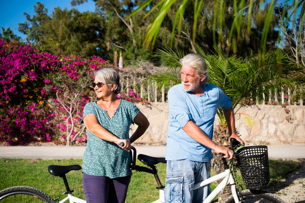 hermosa pareja de mayores y maduros casados, montando una bici doble, tándem, juntos para divertirse con un gran y soleado día - mirando a la espalda  - Foto, Imagen