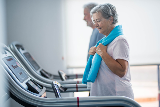 couple of two seniors and mature people training together at the gym - healthy and fitness lifestyle concept - walking in a tapirulan  - Foto, Imagen