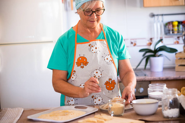 Büyükanne evde balık pişiriyor. Mutfakta. Emekli son sınıf öğrencisi.   - Fotoğraf, Görsel