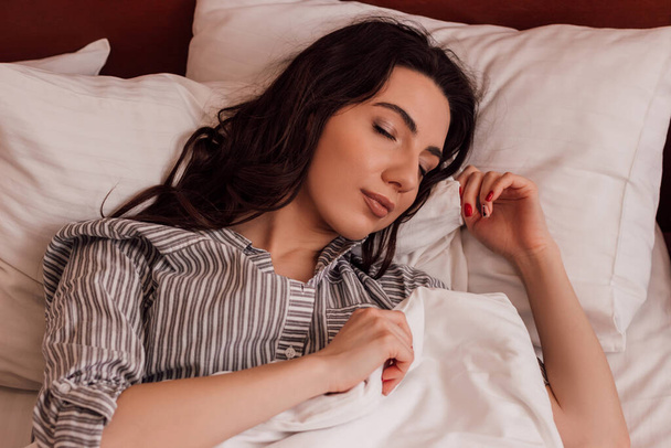 Όνειρο. Όμορφη νεαρή γυναίκα κοιμάται στο κρεβάτι με πιτζάμες. Υψηλής ποιότητας φωτογραφία - Φωτογραφία, εικόνα