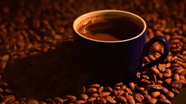 Een kopje koffie op koffiebonen, koffie verlicht door warm licht, koffie op een zwarte achtergrond, slow motion video en hd video. - Video