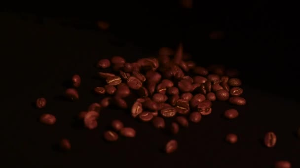Geroosterde Arabica koffiebonen gieten uit en roterende, close-up, bruine bonen vallen te vullen in zakken, hd video en slow motion op zwarte achtergrond. - Video