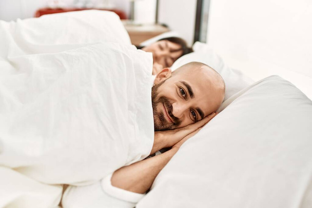 Fiatal spanyol házaspár alszik az ágyon a hálószobában.. - Fotó, kép