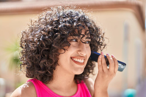 Jeune femme du Moyen-Orient souriant confiant écoute message audio par le smartphone à la salle de jeux - Photo, image