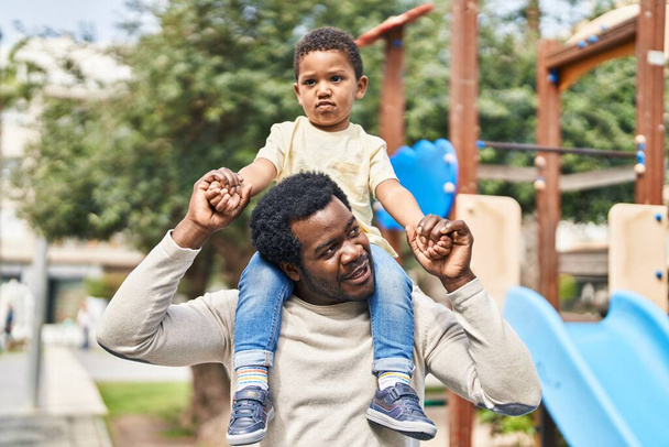 Πατέρας και γιος κρατώντας το αγόρι στους ώμους στην παιδική χαρά - Φωτογραφία, εικόνα