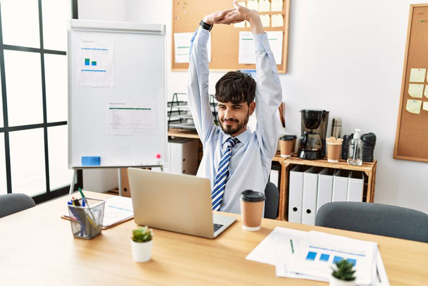 Young hispanic businessman tired stretching arms at the office. - Photo, Image