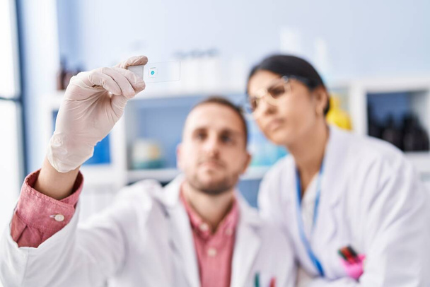 Mężczyzna i kobieta w mundurze naukowca patrząc na próbki w laboratorium - Zdjęcie, obraz