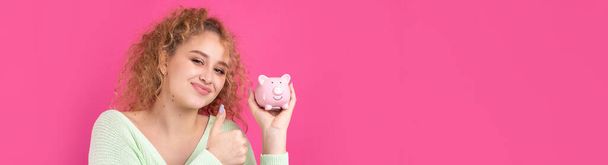 Roztomilá mladá dívka s kudrnatými zrzavými vlasy drží v rukou prasátko s růžovým selátkem. Koncept bohatství a bezpečnosti peněz. - Fotografie, Obrázek