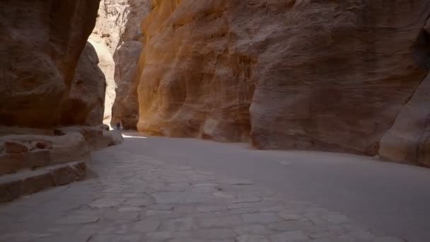 Ein Spaziergang im Siq, der engen steinernen Schlucht, die als Eingangspassage zur versteckten Stadt Petra in Jordanien dient - Filmmaterial, Video
