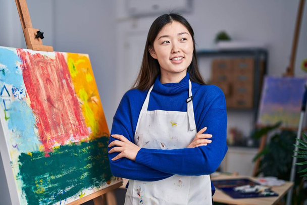 Chinese woman artist smiling confident standing with arms crossed gesture at art studio - Photo, Image