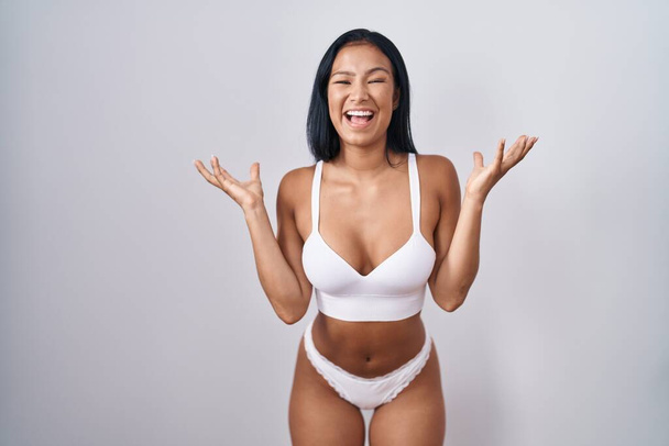 Hispanic woman wearing lingerie celebrating crazy and amazed for success with arms raised and open eyes screaming excited. winner concept  - Photo, Image