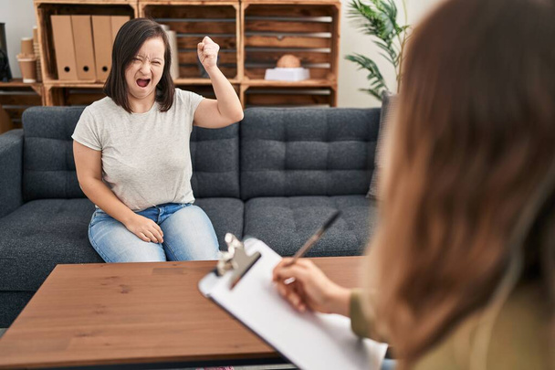Spanyol lány Down-szindróma csinál terápia dühös és őrült emelő ököl frusztrált és dühös, miközben kiabál a harag. düh és agresszív koncepció.  - Fotó, kép