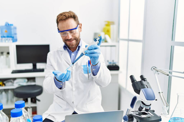 Middle age hispanic man wearing scientist uniform working at laboratory - Photo, Image
