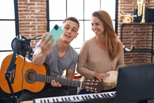 Man and woman musicians having classic guitar lesson make selfie by the smartphone at music studio - Foto, Imagen