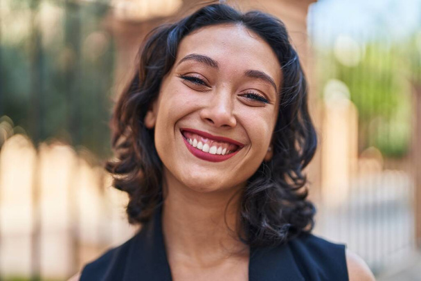 jong mooi latino vrouw glimlachen zelfverzekerd staan op straat - Foto, afbeelding