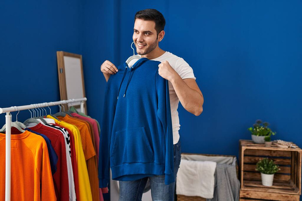 Nuori latino mies laittaa vaatteita vaatteet telineeseen pyykkitupa - Valokuva, kuva
