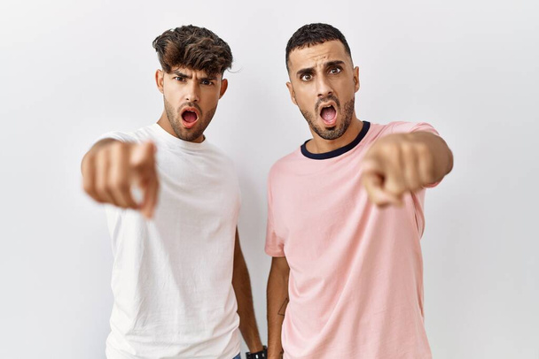 Jeune couple gay debout sur fond isolé pointant mécontent et frustré à la caméra, en colère et furieux contre vous  - Photo, image
