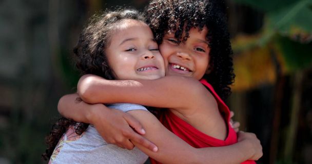 Дети обнимаются. Две маленькие испаноязычные девочки обнимаются - Фото, изображение