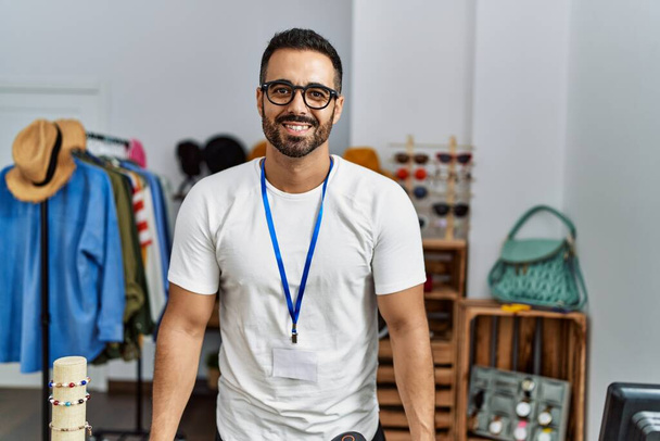若いヒスパニック系の男の店主は、衣料品店で自信を持って働く笑顔 - 写真・画像