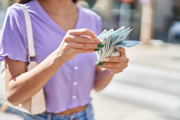 Young beautiful hispanic woman counting dollars at street - Photo, Image